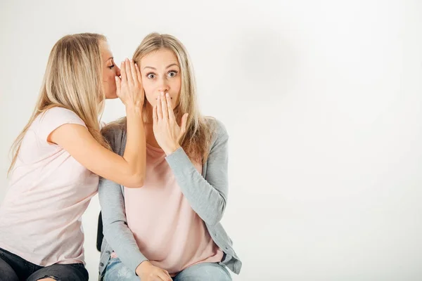 Chica sorprendida mirando a su hermana gemela sobre fondo blanco — Foto de Stock
