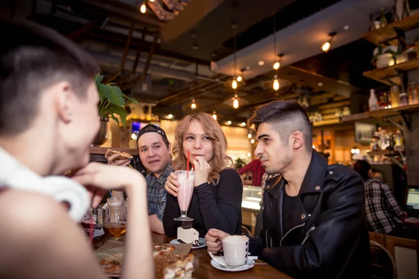 Jovem mulher bebendo milkshake enquanto se senta com amigos no café — Fotografia de Stock