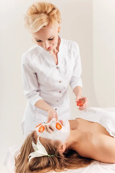 La mujer hermosa joven que recibe la máscara de frutas en el rostro en el salón de belleza - en el interior — Foto de Stock