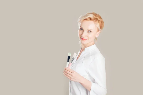 Positiver professioneller Kosmetiker hält Pinsel und Schale in der Hand — Stockfoto