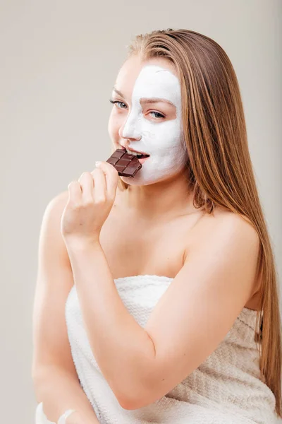 Portrait of beautiful woman with spa mask holding chocolate bar — Stok Foto