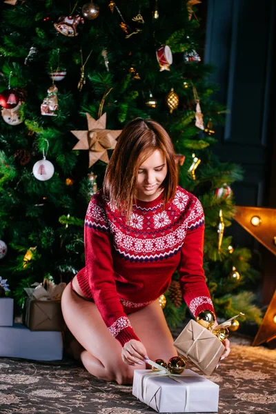 Vacker sexig kvinna i röd jul tröja. Vinter kvinna med julklapp — Stockfoto