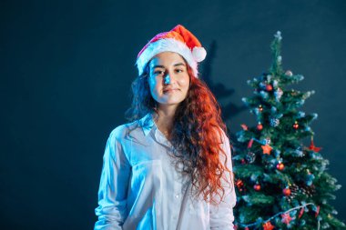 hediyeler ile Noel ağacı yakınındaki santa şapkalı kız