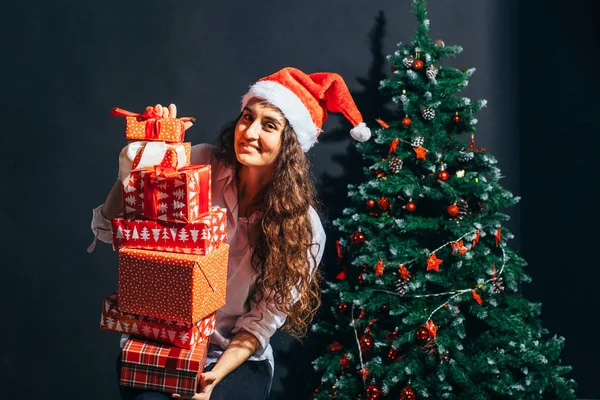 Leende kvinna i santa helper hatt med många presentförpackning — Stockfoto