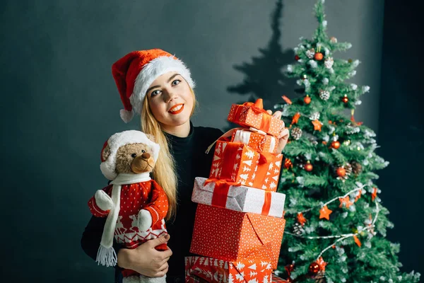 Flicka i santa hatt nära en julgran med gåvor — Stockfoto
