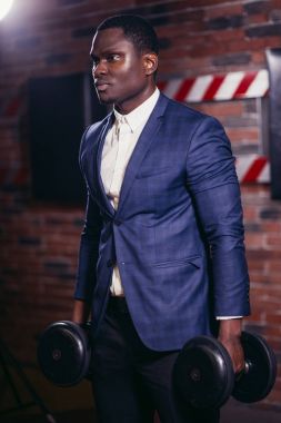 Spor salonunda dambıllarla çalışan sağlıklı bir Afrikalı.