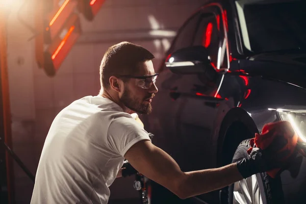 Детализация автомобиля - мужчина держит микроволокно в руке и полирует автомобиль — стоковое фото