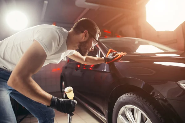 Детализация автомобиля - мужчина держит микроволокно в руке и полирует автомобиль — стоковое фото