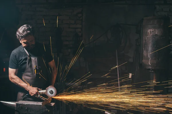 Hombre usando amoladora angular en fábrica y lanzando chispas —  Fotos de Stock