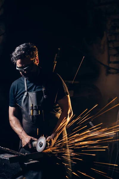 Hombre usando amoladora angular en fábrica y lanzando chispas — Foto de Stock