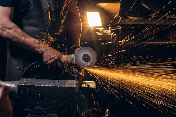 man Using Angle Grinder in Factory and throwing sparks