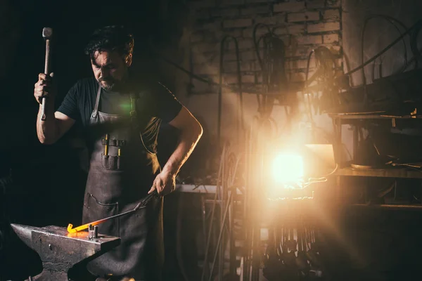 Herrero forja manualmente metal fundido en yunque en la herrería con fuegos artificiales chispa —  Fotos de Stock