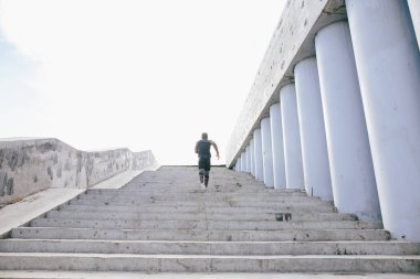 Afrikalı siyah sporcu stadyum tribünlerinde enerjisiyle yukarı doğru koşuyor.