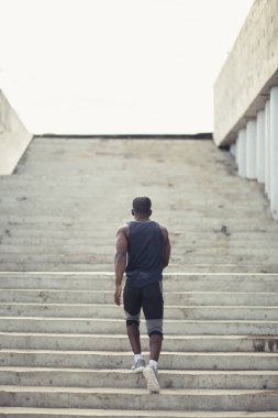 Arkadan görünüş merdiven bina dışında çalışan bir erkek atlet