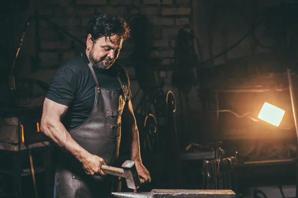 Ferreiro trabalhando metal com martelo na bigorna na forja — Fotografia de Stock