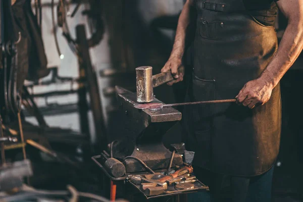 Blacksmith manually forging the molten metal on the anvil in smithy — Stock Photo, Image