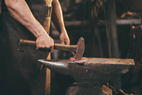 Blacksmith working on metal on anvil at forge