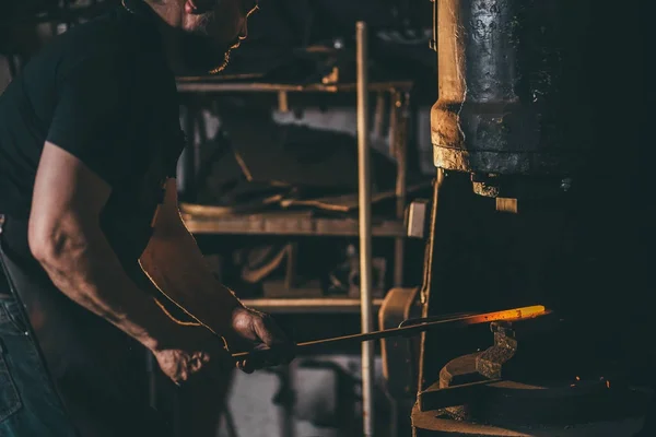 Taller de herrero. hombre pone pieza forjada bajo un martillo automático —  Fotos de Stock