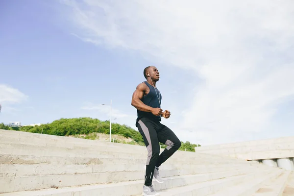 Afrikanischer schwarzer Sportler läuft auf der Stadiontribüne energisch nach oben — Stockfoto