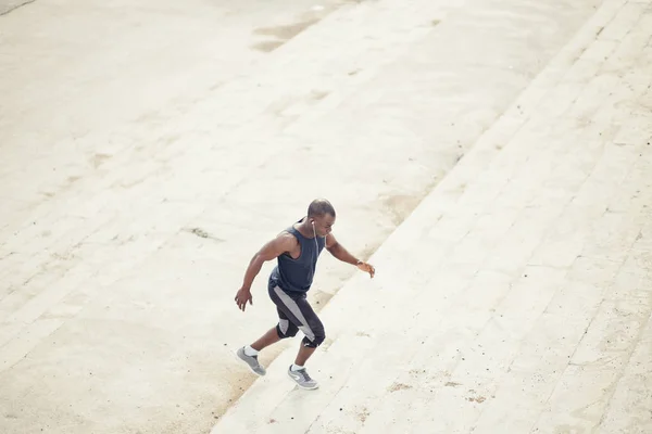 Side view of a male athlete running up staircase outside building — Stock Photo, Image