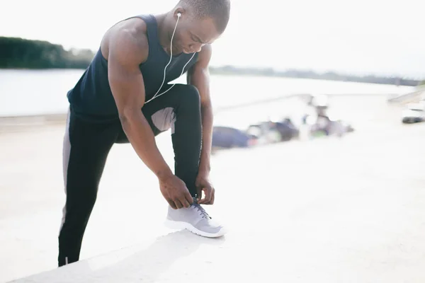 Junger schwarzer Läufer bindet seine Schnürsenkel — Stockfoto