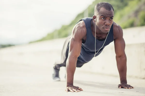 Portret van een jonge zwarte man doet push ups op het strand — Stockfoto