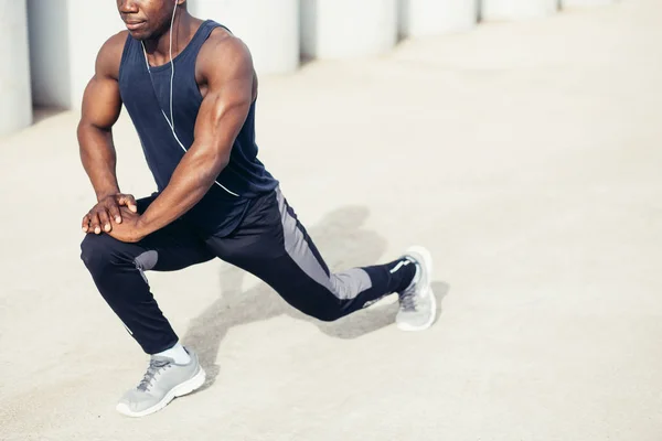 Loper in zwarte sportkleding benen rekken voordat ochtend training — Stockfoto