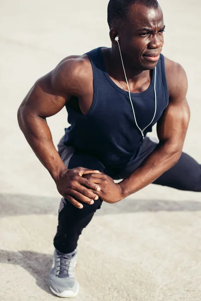 Löpare i svart sportkläder stretching benen innan morgon träning — Stockfoto