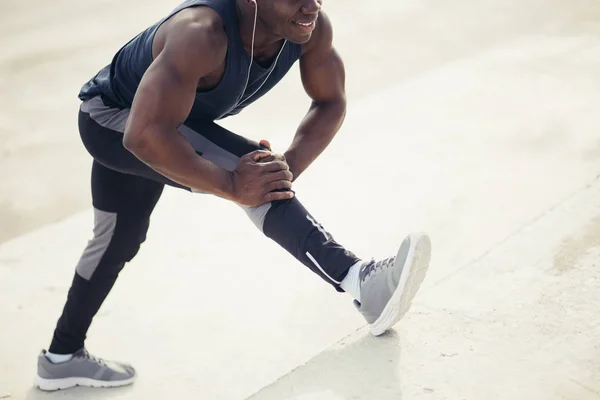 Läufer in schwarzer Sportbekleidung streckt Beine vor dem morgendlichen Training — Stockfoto