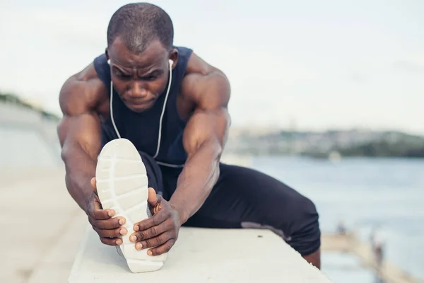 Löpare i svart sportkläder stretching benen innan morgon träning — Stockfoto