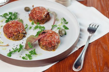 Taş bir plaka üzerinde bir yumurta ile biftek tartar. Kiraz domates. Rosemary. Baharat.