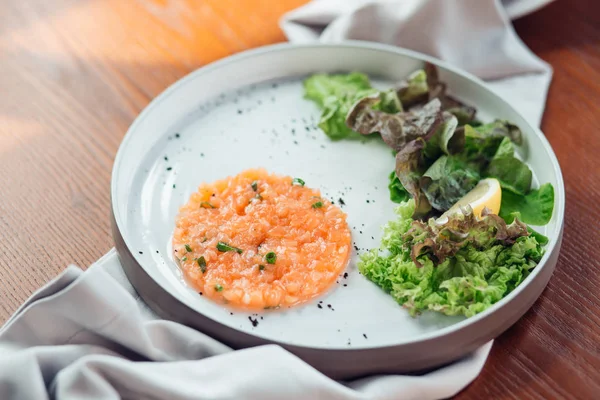 Tartar de salmón con limón y ensalada en plato blanco — Foto de Stock