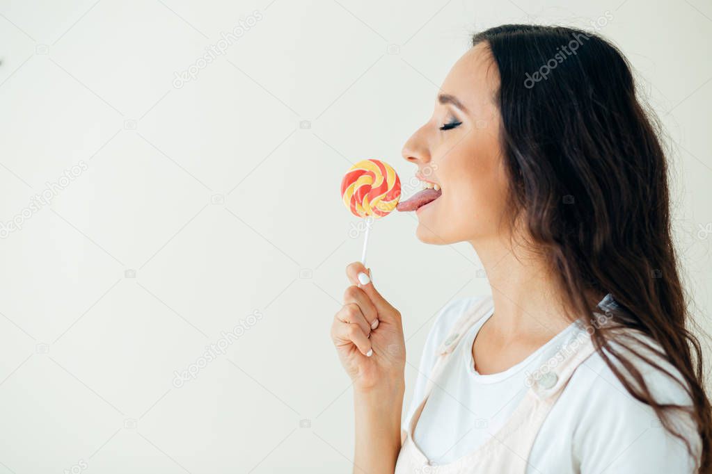 Fashion pretty sweet young woman enjoying a taste lollipop