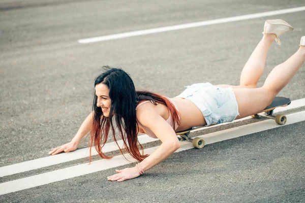 Vista lateral de la joven mujer hipster acostada en el monopatín — Foto de Stock