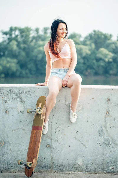 Imagen en blanco y negro de una joven sentada en escaleras sosteniendo longboard — Foto de Stock