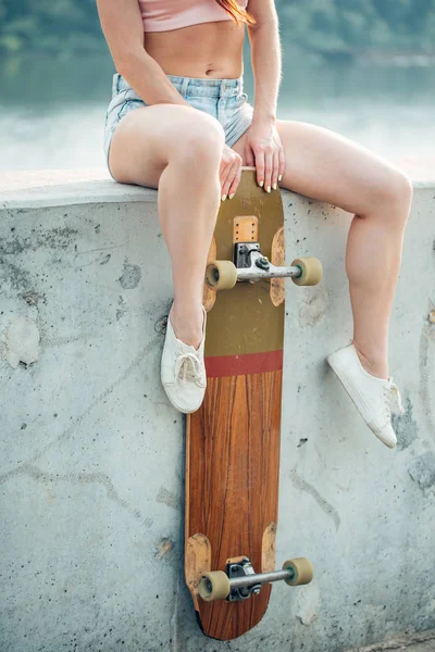 Casual blonde vrouw in denim shirt poseren op de trap met longboard — Stockfoto