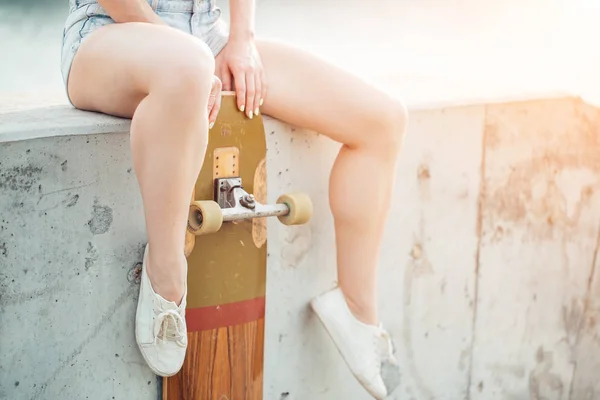 Zwart-wit beeld van jonge vrouw zittend op trap met longboard — Stockfoto