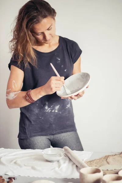 Mujer alfarera pinta taza de cerámica. Mujer trabajando en su estudio de cerámica — Foto de Stock