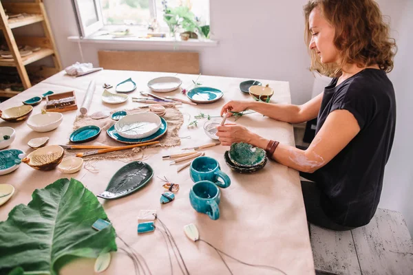 Mujer alfarera pinta taza de cerámica. Mujer trabajando en su estudio de cerámica — Foto de Stock