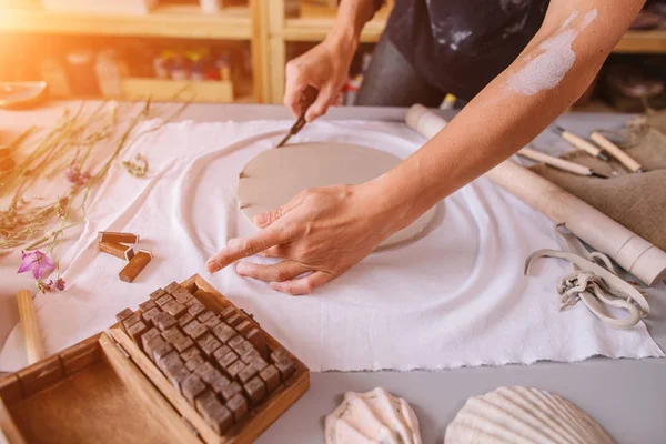 Keramikmeister reibt einen Teller mit gebackenem Ton. eine kreative Werkstatt. — Stockfoto