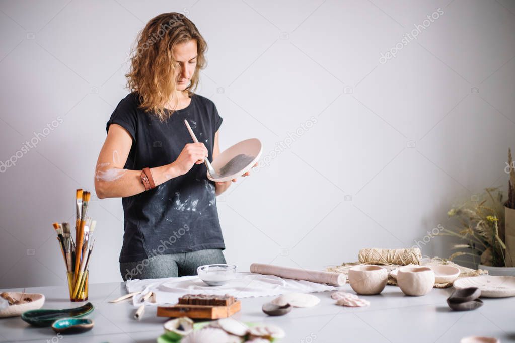 Potter molds a cup of clay. The young potter decorates a cup of clay