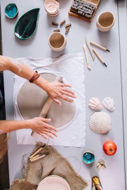 Kadın çömlekçi ustası seramik ürünlerle birlikte masayı topluyor.