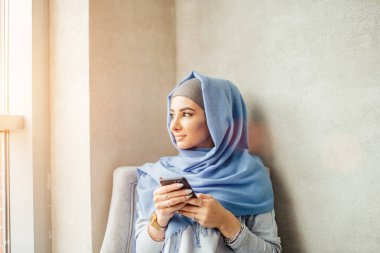Müslüman kadının kafede bir cep telefonuna ileti