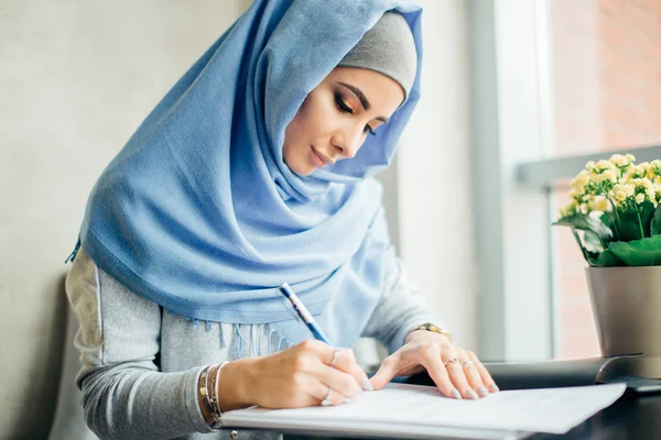 Мусульманка-предпринимательница работает с документами в кафе — стоковое фото