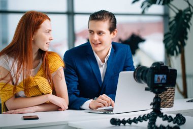 İki video blogcusu bir şey hakkında konuşuyor ve gülümsüyor.