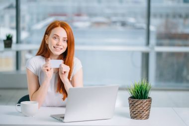 Kadın evde dizüstü bilgisayarıyla alışveriş yapıyor.