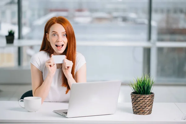 Shocking redhead woman with laptop and credit card