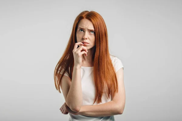 Redhead young Caucasian woman holding arm on her chin and looking up sideways — Stock Photo, Image