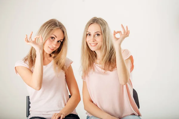 Hermosas mujeres gemelas con maquillaje natural y pelo largo mostrando gesto ok . — Foto de Stock