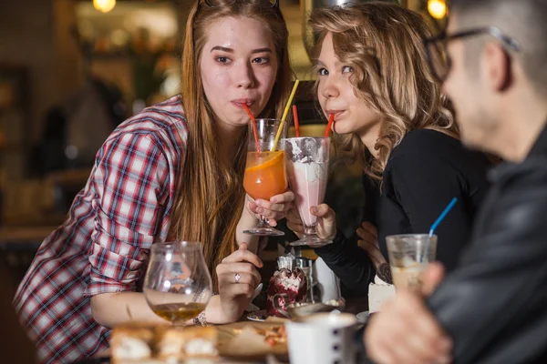카페에서 친구 들과 함께 앉아있는 동안 밀크 쉐이크를 마시는 젊은 여자 — 스톡 사진